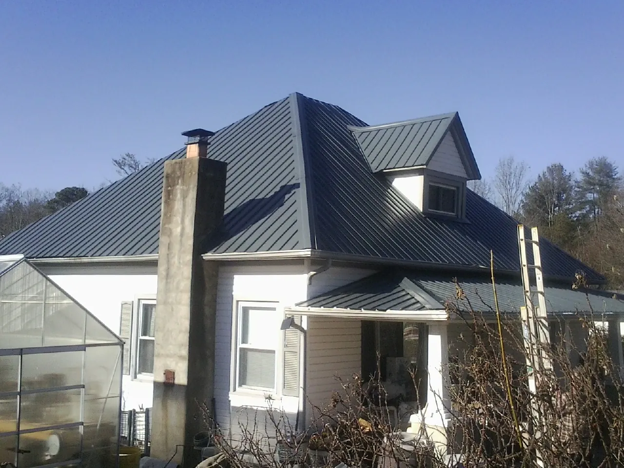 Dark blue standing seam metal roof on a white farmhouse with dormer — Slate & Tile Roof Repair by Roofing Brothers in Lafayette Hill