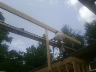 Carpenter setting a ridge beam over a new addition frame — Ice Dam Removal by Roofing Brothers in Lafayette Hill