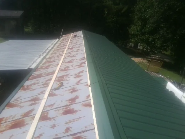 Old rusted panels beside newly installed green metal roofing — Wind Damage Roof Repair by Roofing Brothers in Lafayette Hill