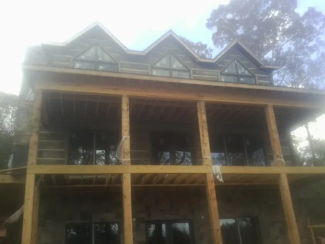 Dormers and porch framing on a large log home under construction — Roof Coating work by our crew in Lafayette Hill