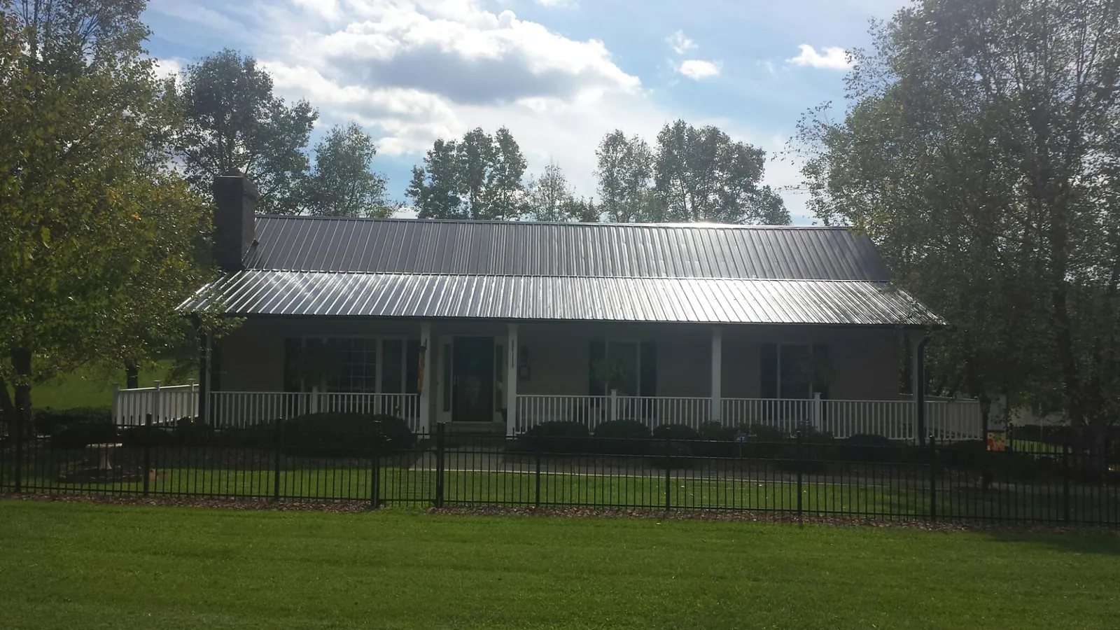 Gray metal roof on a brick ranch with a full width front porch — Gutter Guard Installation work by our crew in Lafayette Hill