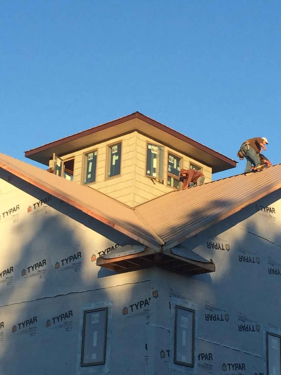 Roofers working around a rooftop cupola on a new metal roof at sunset — Roof Waterproofing in Lafayette Hill by Roofing Brothers